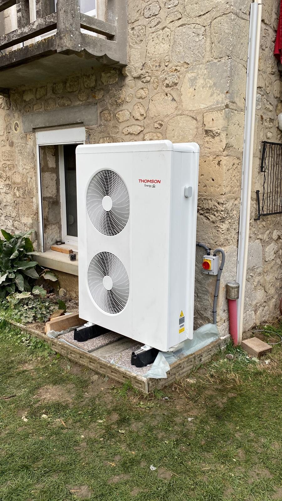 Groupe de pompe à chaleur air-eau au pied d'une maison en pierre
